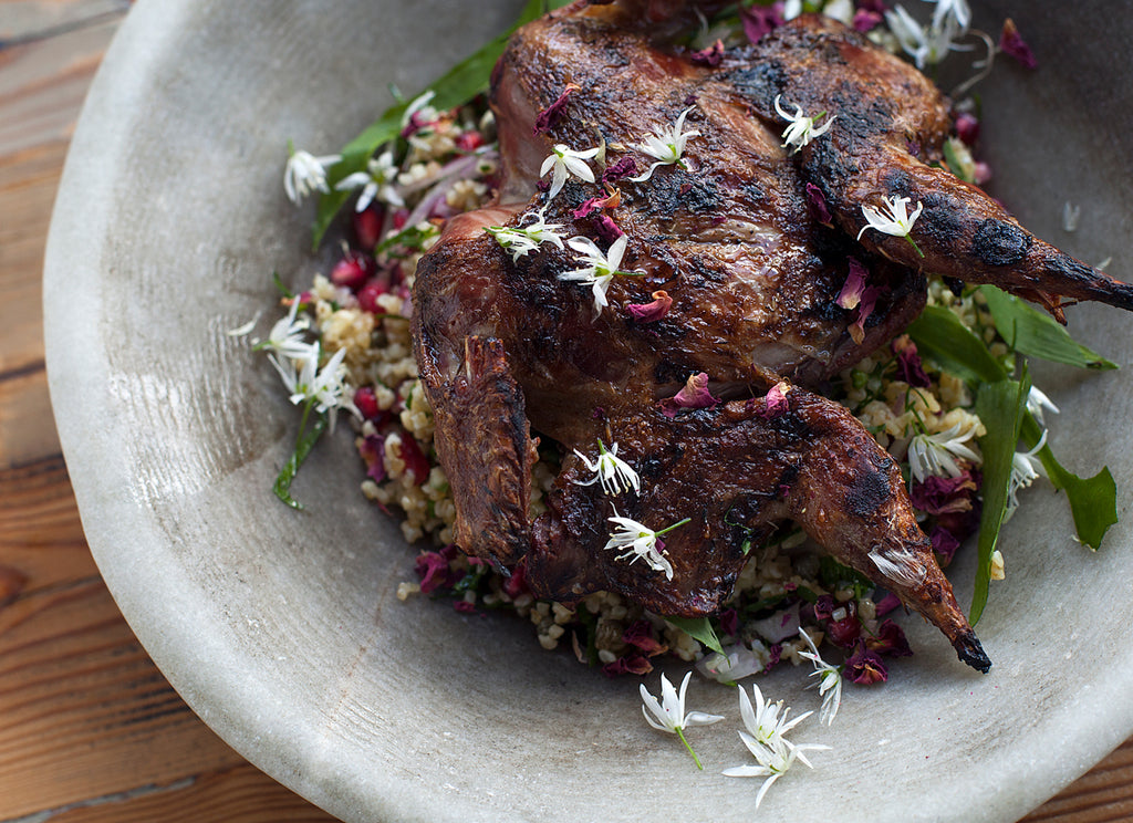 Grey bowl with salad, edible flowers and chargrilled spatchcock grouse on top